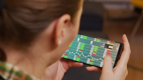 Una mujer observa datos del mercado bursátil y gráficos financieros en la pantalla de su teléfono móvil.