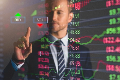 Un hombre de traje interactúa con una pantalla táctil digital que muestra datos bursátiles y opciones para comprar (BUY) o vender (SELL).