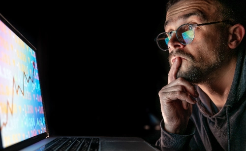 Hombre analizando gráficos del mercado bursátil en un tablero electrónico durante su primer mes de trading real