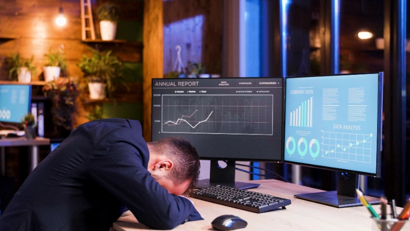 Revenge trading: hombre de negocios agotado con la cabeza sobre la mesa a la luz de la luna