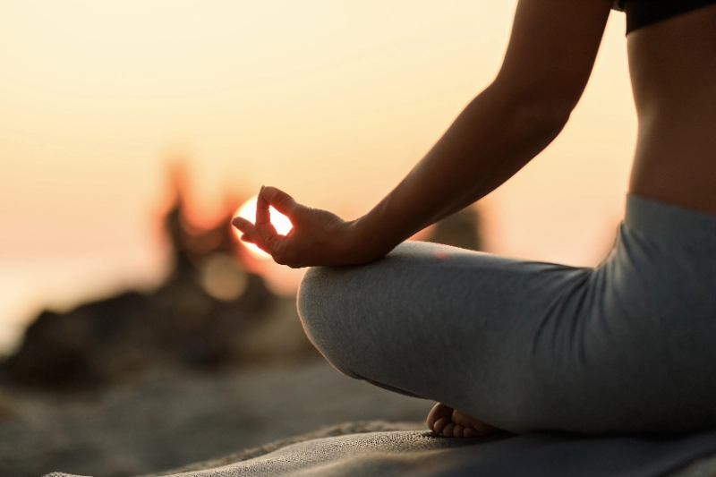 Mindfulness en trading: mujer meditando en posición de loto al atardecer