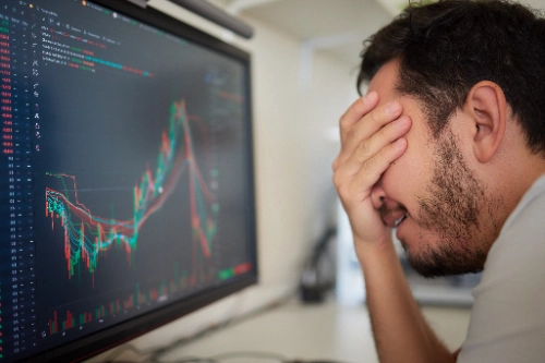 Trader analizando índices en el monitor durante una racha de pérdidas o drawdown