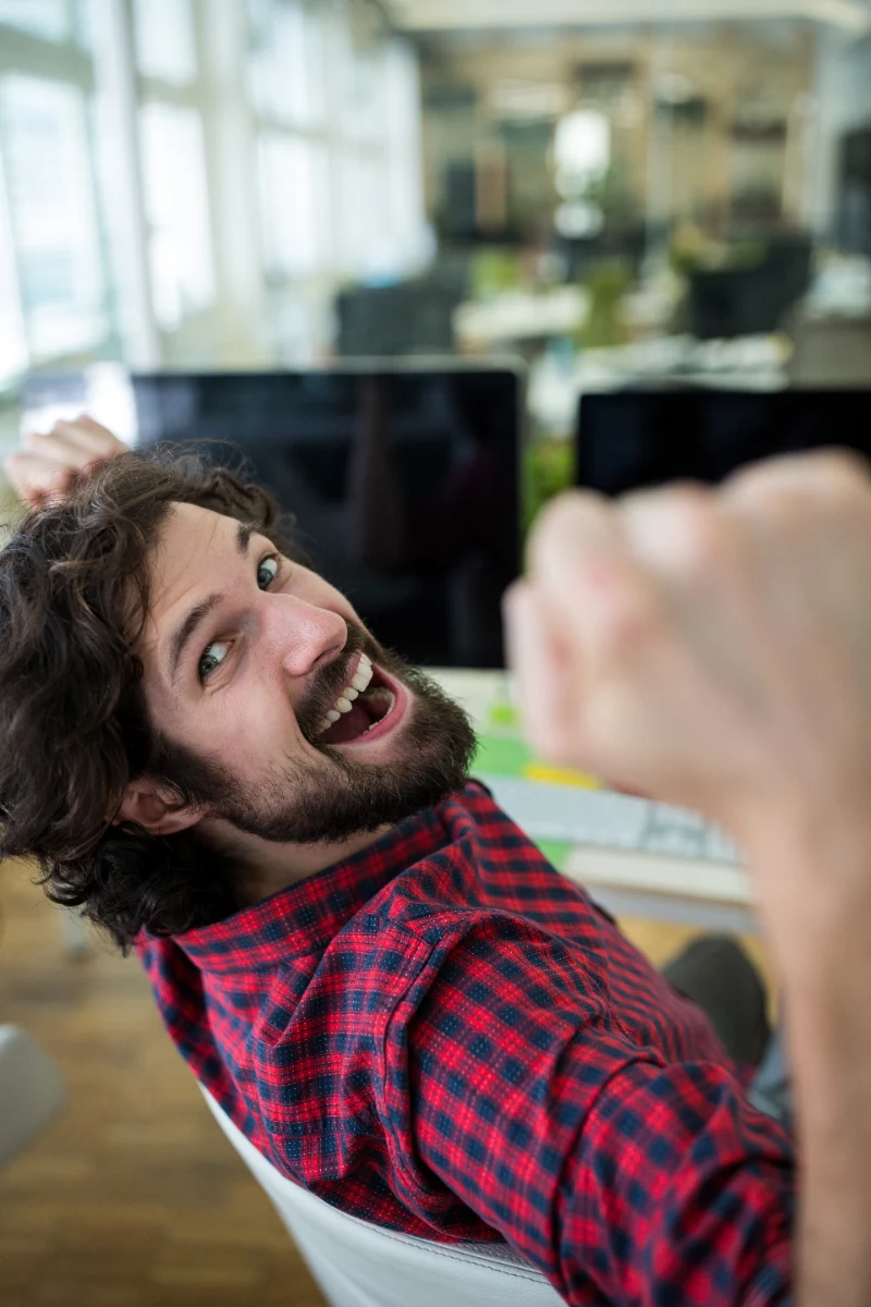Euforia en trading: hombre celebrando en la oficina tras una racha ganadora
