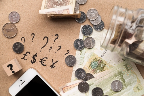 Ahorro y divisas junto a un smartphone, representando la relación entre pares de divisas
