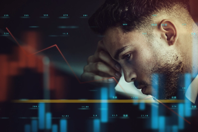 Parálisis por análisis en trading: hombre con dolor de cabeza rodeado de gráficos de análisis
