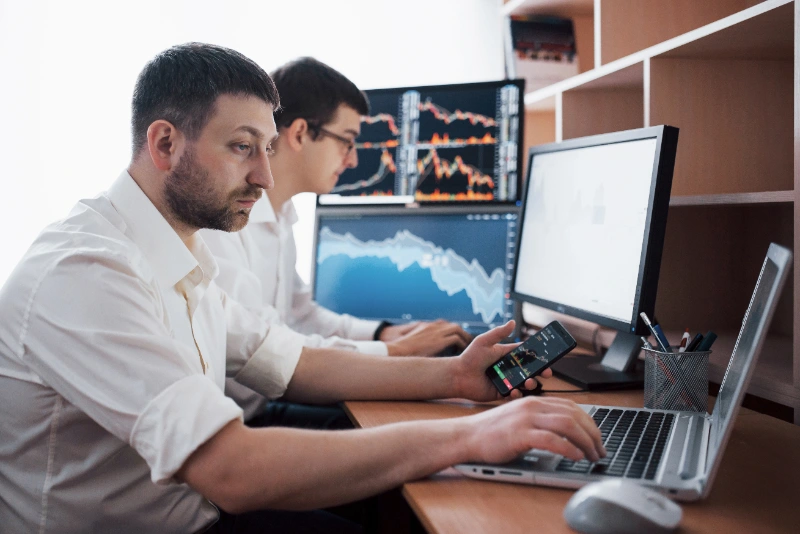 Equipo de traders analizando gráficos y datos de inversión en pantallas