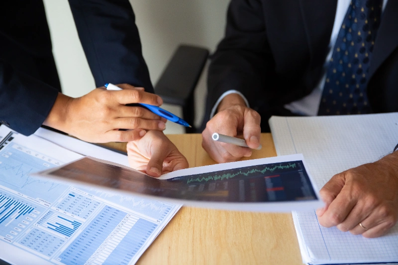 Inversor y bróker discutiendo estrategia de trading con gráficos financieros