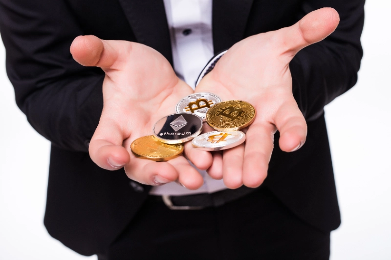 Hombre sosteniendo distintas monedas de criptomonedas en sus manos