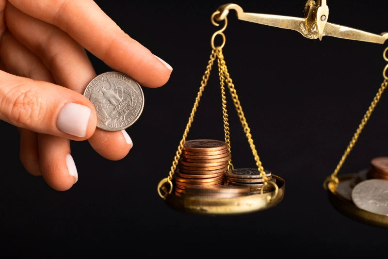 Monedas de dólar sobre una balanza, metáfora del equilibrio y desequilibrio del precio
