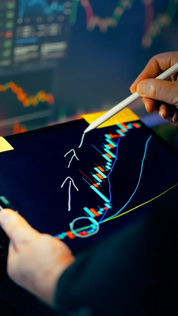 Operador marcando una tendencia alcista con un lápiz óptico en una tableta con gráficos de velas, representando el análisis técnico y la especulación en criptomonedas.